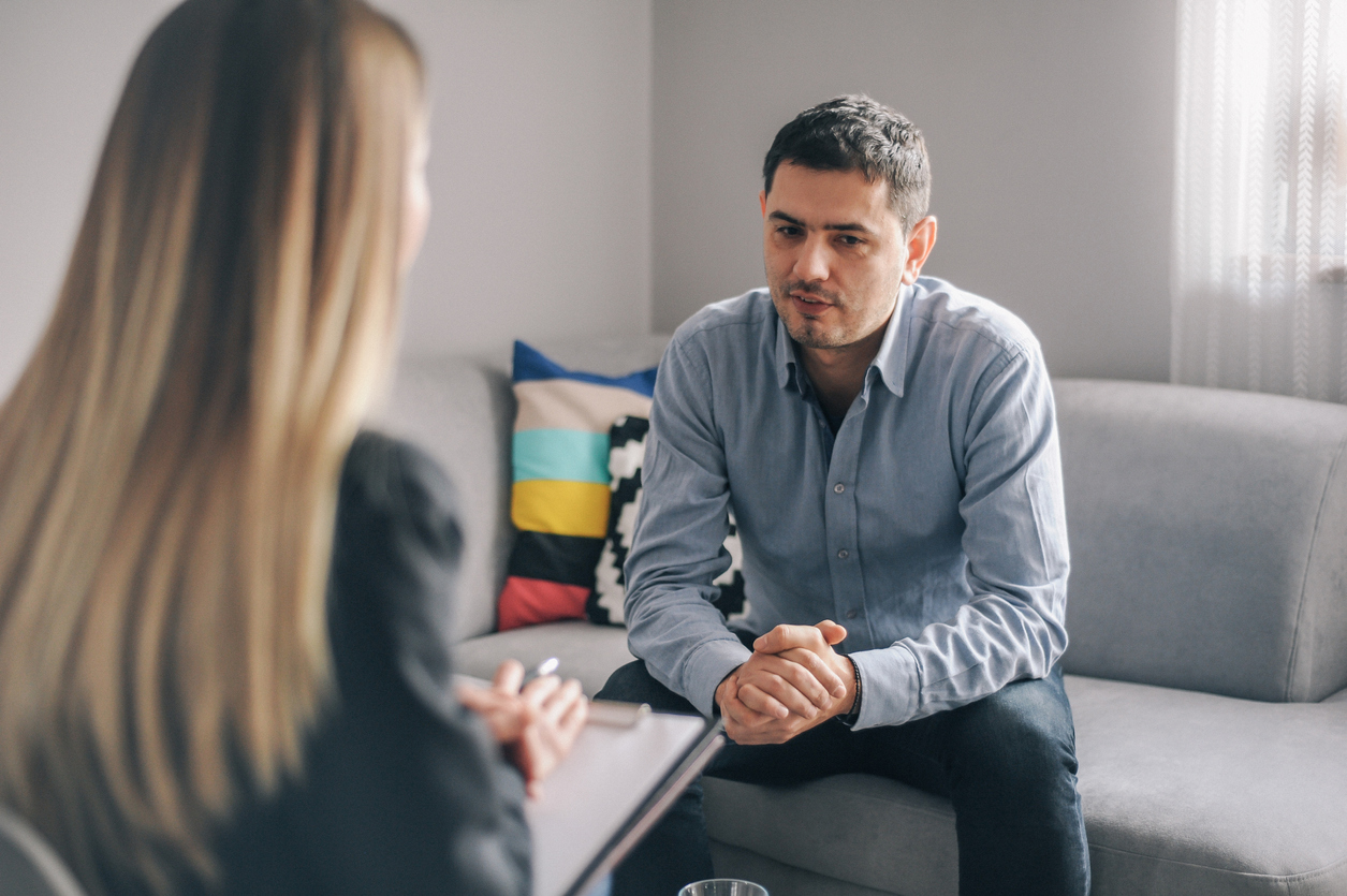 man sits on couch chatting to therapist