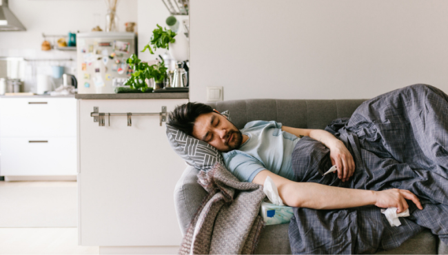 man laying on couch while sick