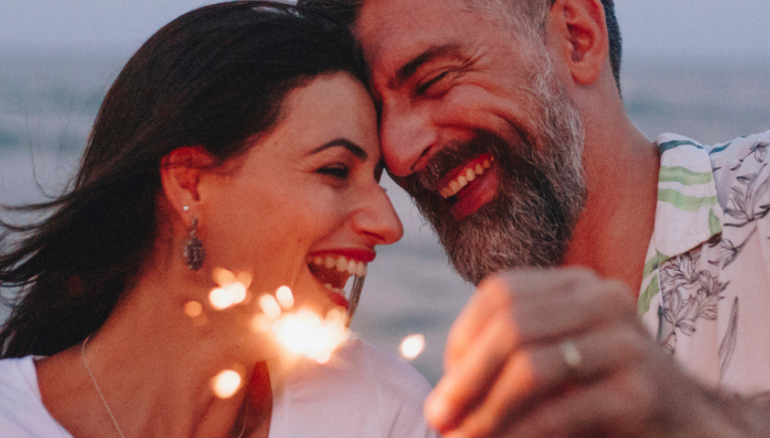 couple smiling on beach holding sparklers