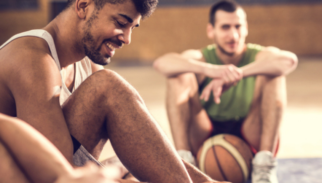 Group of young men sitting on floor after playing indoor basketball