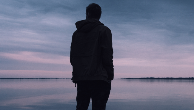 man standing alone looking out at water