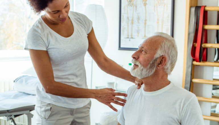 older man works with physiotherapist