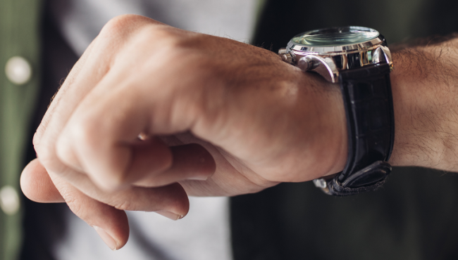 Man in grey tshirt and green shit looking at watch on left wrist